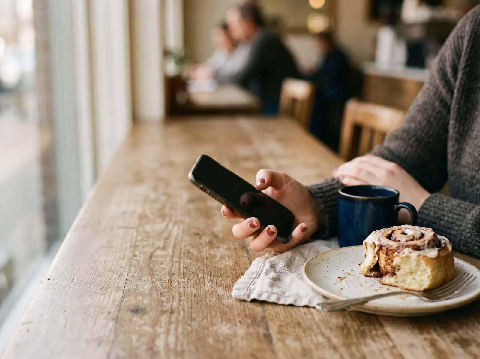 A person holding a phone at a cafe table